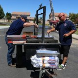 A pair of volunteer firefighters cook up a bunch of hot dogs at Saturday's block party.